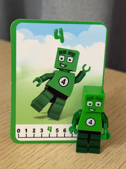 Numberblocks building blocks toy set featuring green character number 4 with matching card on a wooden surface.